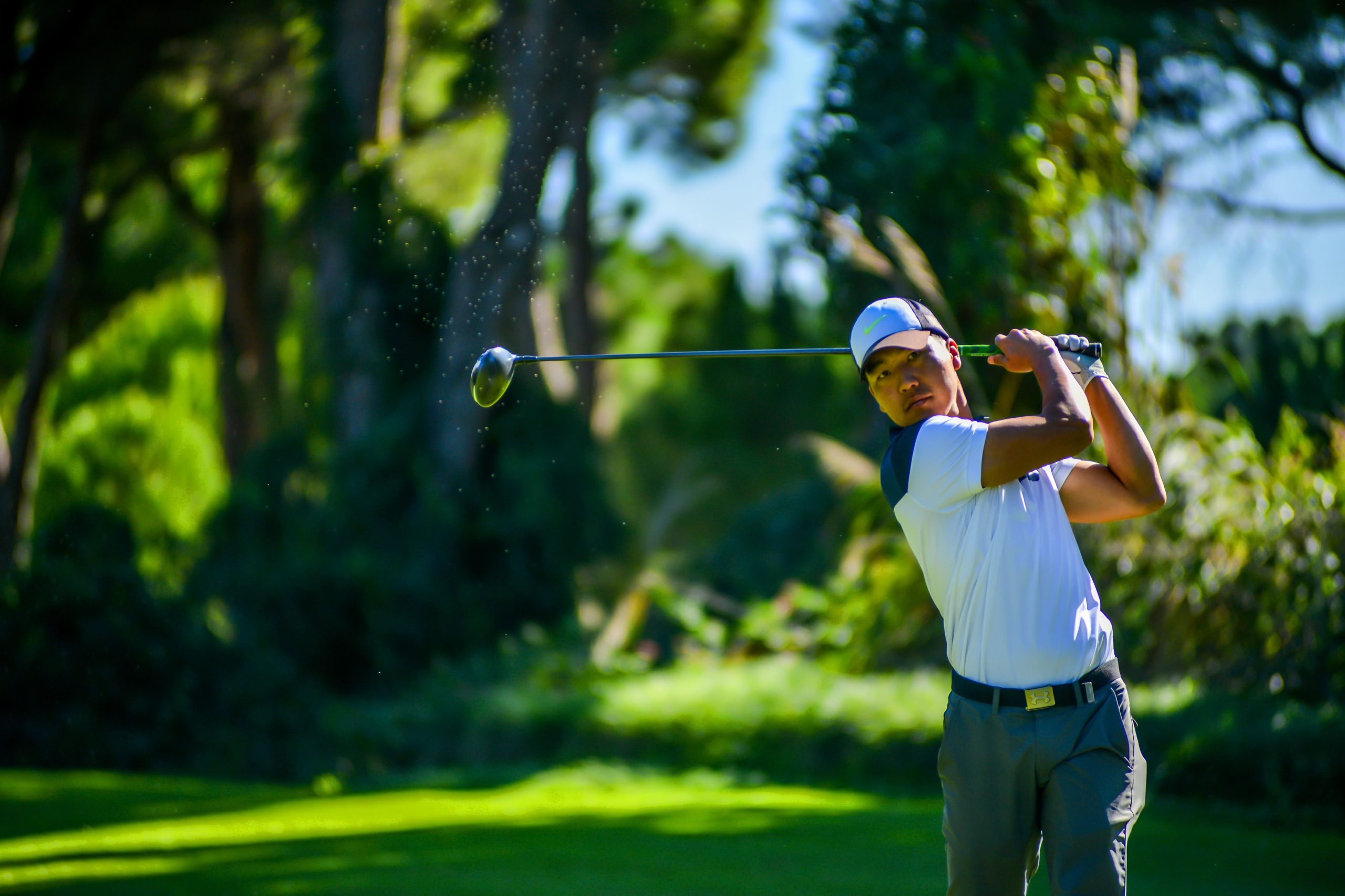 Man playing golf in mid-swing against a blurred background of green grass and trees. Degenerative disc disease treatment options